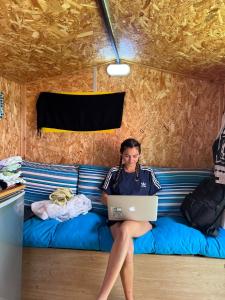 a woman sitting on a couch with a laptop at Roger's Hostel Tel Aviv (age 18-45) in Tel Aviv