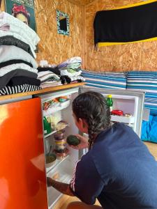 a woman is looking into an open refrigerator at Roger's Hostel Tel Aviv (age 18-45) in Tel Aviv