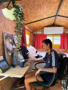 une femme assise sur un bureau avec un ordinateur portable dans l'établissement Roger's Hostel Tel Aviv (age 18-45), à Tel Aviv