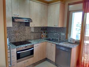 a kitchen with wooden cabinets and a sink and a window at Apartamento En Mediterráneo Real, Los Boliches, Fuengirola in Fuengirola