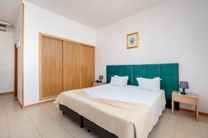 a bedroom with a large bed with a green headboard at Hotel Santa Catarina Algarve in Portimão
