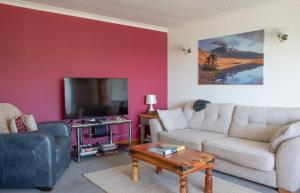 a living room with a couch and a tv at Tarradale Cottage in Portree