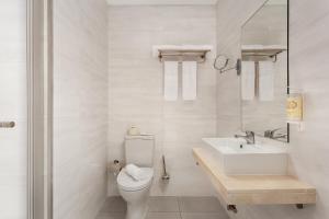 a white bathroom with a toilet and a sink at Empire Marquês Hotel in Lisbon