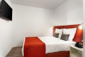 a hotel room with a bed and a television at Empire Marquês Hotel in Lisbon