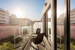two chairs on a balcony with a view of a city at Empire Marquês Hotel in Lisbon