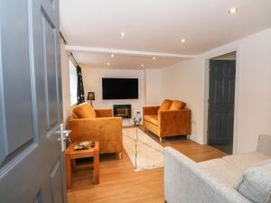ein Wohnzimmer mit 2 Stühlen und einem TV in der Unterkunft Butterfly Cottage in Rossendale