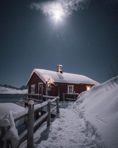a barn covered in snow at night with the moon at Svinøya Rorbuer in Svolvær