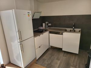 uma cozinha com armários brancos e um frigorífico branco em Ferienhaus meurastein 