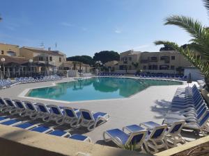 une grande piscine avec des chaises longues et des palmiers dans l'établissement Studio climatisé cosy avec grande piscine chauffée, au Cap d'Agde