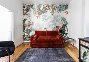 un sofá rojo sentado en una sala de estar con una pared en 123paris city, en París