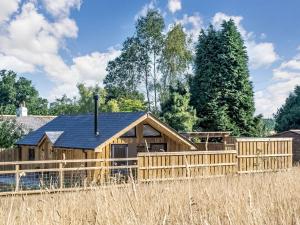 a log cabin with a fence and trees at Olchard Lodge in Ideford