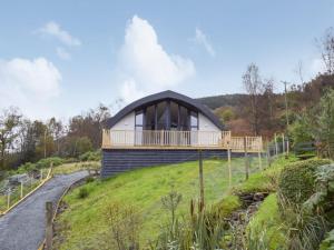 a house on top of a grassy hill with a building at The Lodge at Braemor in Arrochar