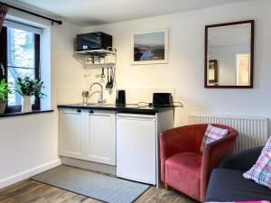 a kitchen with a sink and a chair in a room at The Farmers Den in Lydford