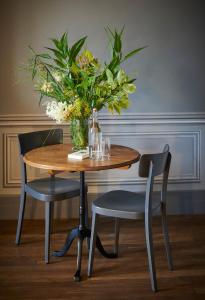 una mesa con un jarrón de flores y dos sillas en Château de Sibra en Lagarde