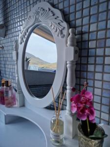 un espejo blanco en un mostrador con un jarrón de flores en Guesthouse Hugo, en Sørvágur