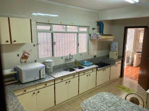 eine Küche mit einer Spüle und einer Mikrowelle in der Unterkunft Ampla Casa em condomínio in Foz do Iguaçu