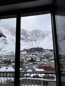 a view of a snowy mountain from a window at Maia's Guest House Gergeti in Stepantsminda