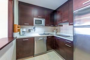 kuchnia z drewnianymi szafkami i lodówką ze stali nierdzewnej w obiekcie 797 HOLIDAY RENTALS - ARCOSUR1- Moderno apartamento con terraza y vistas w mieście Benalmádena