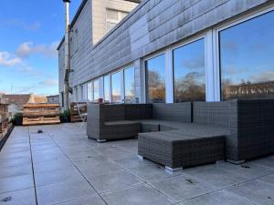 - une terrasse avec 2 bancs en osier dans un bâtiment dans l'établissement Zentrales großzügiges Apartment mit Dachterrasse!, à Bochum