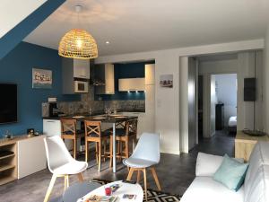 a living room and kitchen with blue walls and white chairs at Le Saint-Patern - T3 centre-ville et garage sécurisé in Vannes