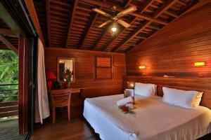 a bedroom with a bed with a ceiling fan and a desk at Jardin Malanga in Basse-Terre