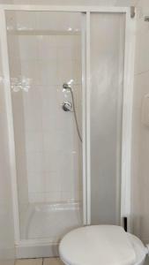 a white bathroom with a shower with a toilet at MINI HOUSE in Montescaglioso