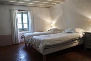 2 camas en una habitación blanca con ventana en La Cour du Marronnier, en Pont-de-Barret