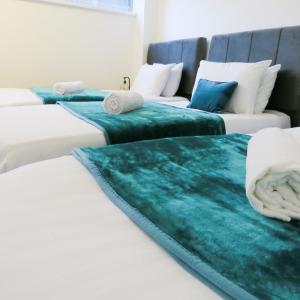 a group of three beds in a room at Tudors eSuites Five Ways Private Terrace & Parking in Birmingham