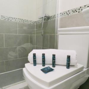 a bathroom with a toilet with towels on it at Tudors eSuites Five Ways Private Terrace & Parking in Birmingham