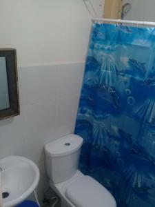 a bathroom with a toilet and a blue shower curtain at EKONUMI ROOMS at Moonwalk Paranaque in Manila