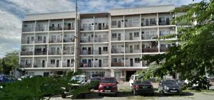 マニラにあるEKONUMI ROOMS at Moonwalk Paranaqueの大きな白い建物とその前に駐車された車