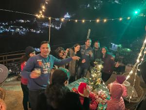 a group of people standing around a table with a christmas tree at Vanshika homes Near mall road in Kasauli