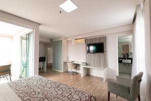 a bedroom with a bed and a desk and a television at IT Itabira Hotel in Itabira