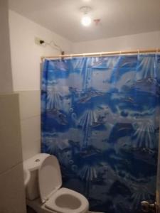 a bathroom with a blue shower curtain and a toilet at EKONUMI ROOMS at Moonwalk Paranaque in Manila