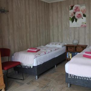 a room with two beds and a red chair at B&B de Linde in Hoogeveen