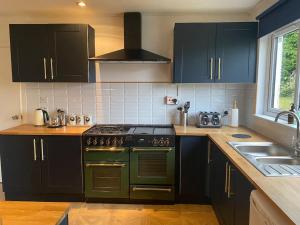 een keuken met een groene kachel en een wastafel bij Dunmara: Self Catering Cottage on the Isle of Skye in Broadford