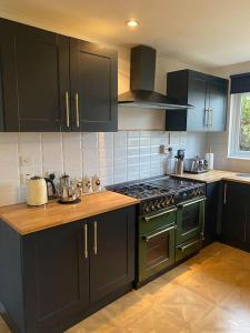 een keuken met zwarte kasten en een groene oven bij Dunmara: Self Catering Cottage on the Isle of Skye in Broadford