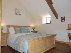 una camera con un grande letto con struttura in legno di Dolgoy Coach House Loft a Llwyn-Dafydd