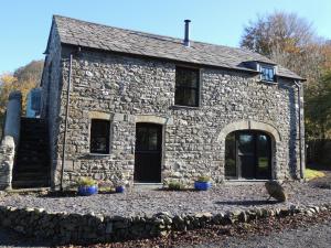 una casa de piedra con plantas delante de ella en Dolgoy Coach House Loft en Llwyn-Dafydd