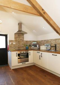 cocina con armarios blancos y fogones en Dolgoy Coach House Loft en Llwyn-Dafydd