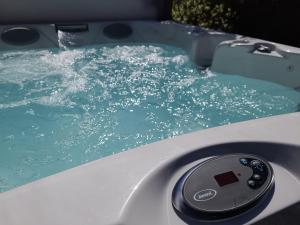 a bath tub filled with blue water with a remote control at Ponycob hot tub 2 bed ensuite in Llwyn-Dafydd +47 photos