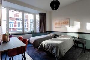 Habitación de hotel con 2 camas y mesa en Hey - Aparthotel Brussels en Bruselas