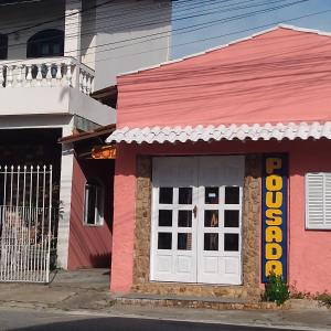 różowy budynek z białymi drzwiami na ulicy w obiekcie Pousada Sol de Verão w mieście São Pedro da Aldeia