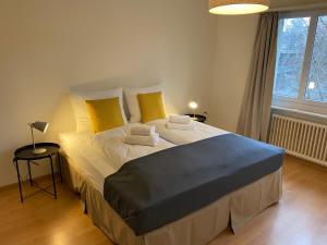 Comfort 1 and 2BDR Apartment close to Zurich Airport في زيورخ: غرفة نوم بسرير كبير مع مخدات صفراء