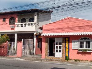 różowy budynek po stronie ulicy w obiekcie Pousada Sol de Verão w mieście São Pedro da Aldeia