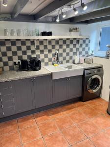 a kitchen with a sink and a washing machine at Coastal Village Cottage in Talacre
