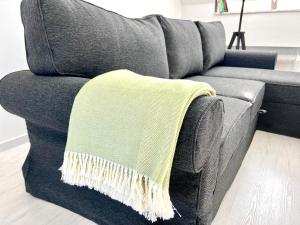 eine graue Couch mit einer gelben Decke drauf. in der Unterkunft Apartament Aviator in Mielec