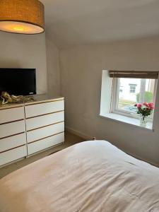 a bedroom with a bed and a tv and a window at Coastal Village Cottage in Talacre