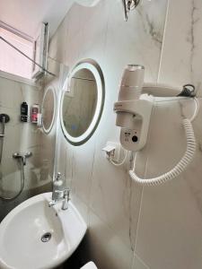 ein weißes Badezimmer mit einem Waschbecken und einem Spiegel in der Unterkunft Happy Traveller SKG in Thessaloniki