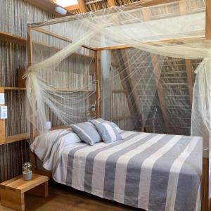 a bedroom with a canopy bed with blue pillows at Peaceful beachside artist-designed in Puerto Escondido